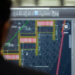 Steel detailer reviewing a 3D structural steel model and fabrication drawings
